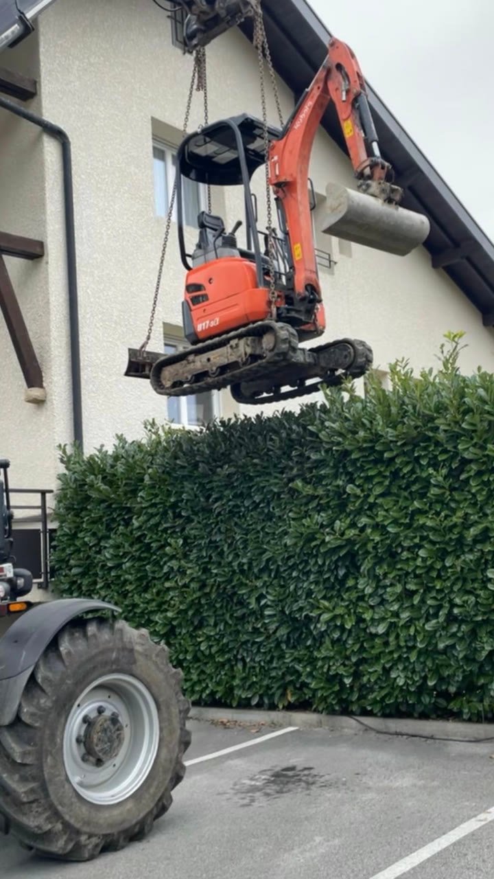 Mini-pelle déposée à la grue sur un chantier