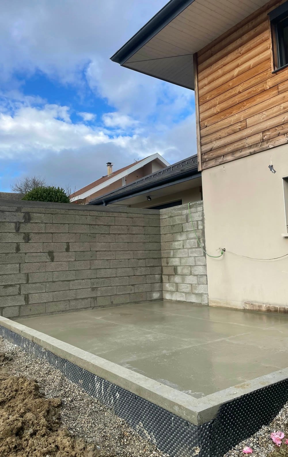 Terrasse béton bordée d'un muret en parpaing