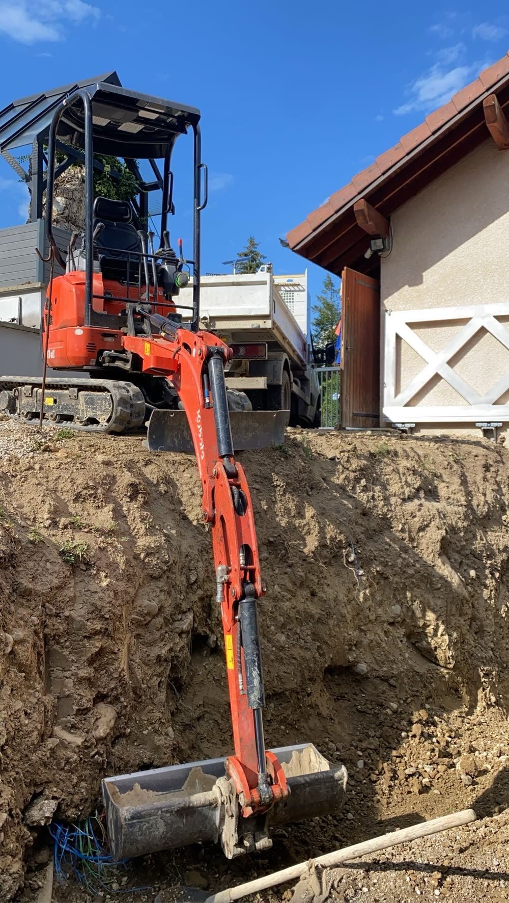 Mini-pelle et camion benne lors d'un terrassement en pied de maison en Haute-Savoie