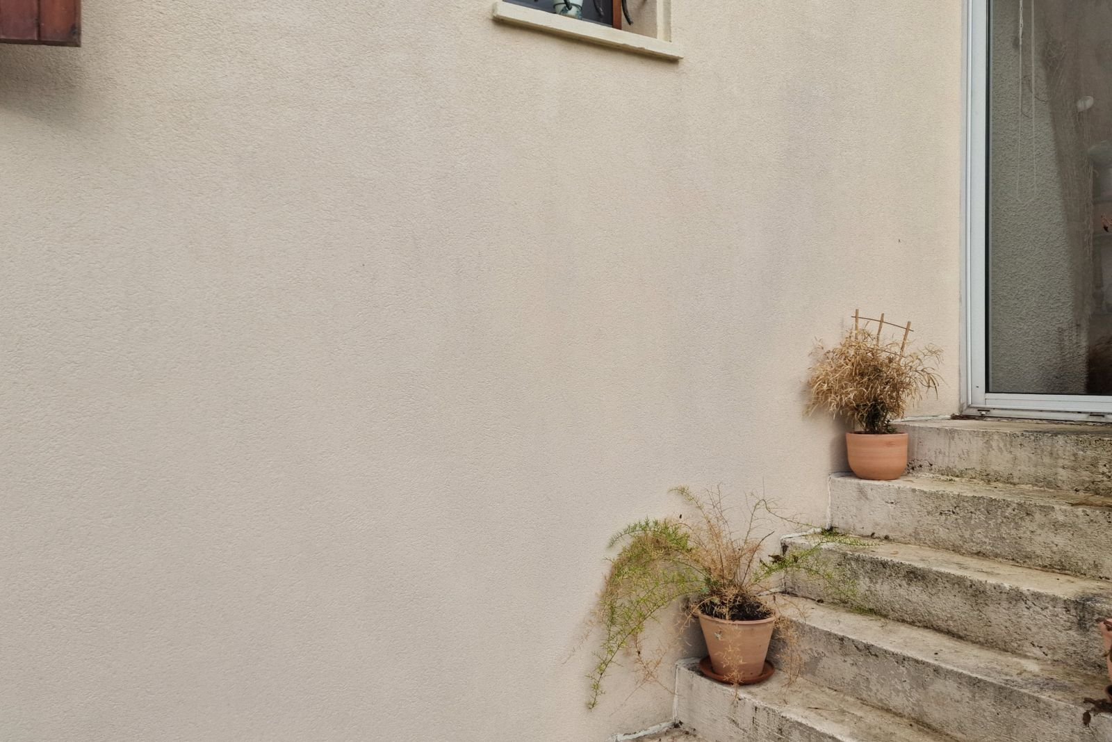 Façade enduite et escalier extérieur en pierre après rénovation